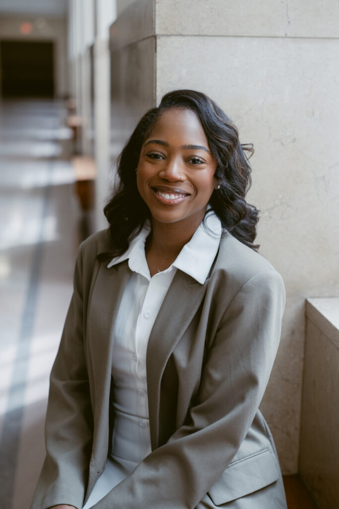 Professional headshot of smiling woman in blazer and white blouse, natural indoor light.