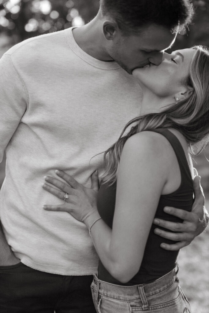 Couple sharing a kiss while standing close, intimate and relaxed black and white moment