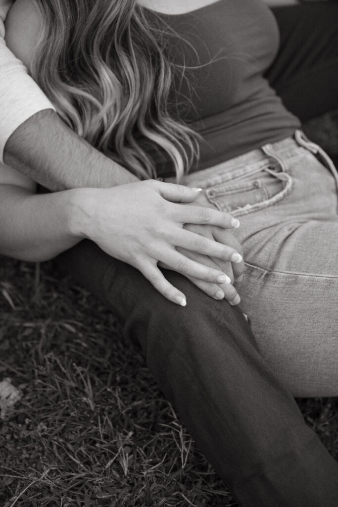 Close up of hands resting together on lap, soft and quiet detail shot on grass