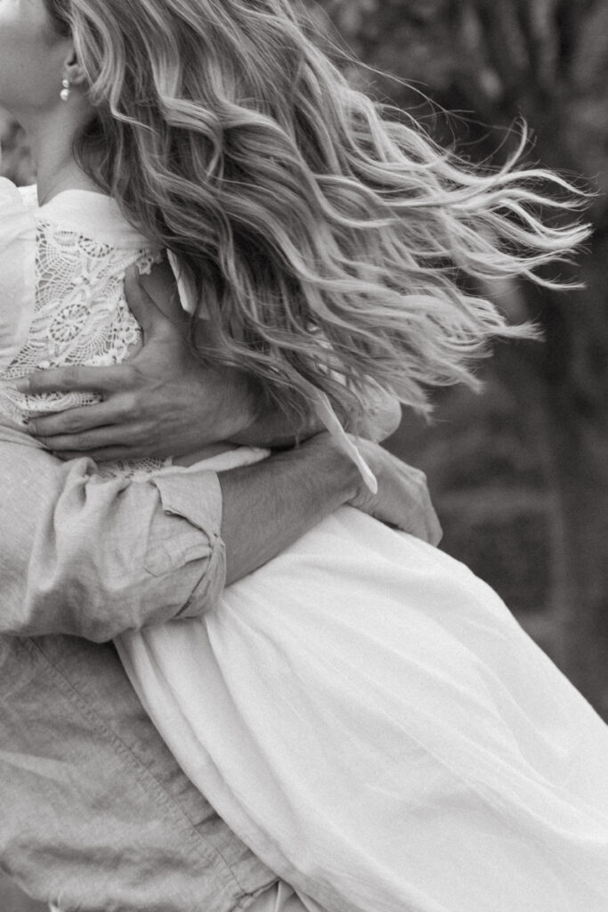 Close up of couple embracing with flowing hair and dress, soft movement in black and white