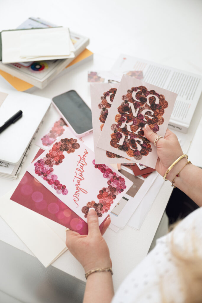 Close up of hands holding colorful branding cards and printed marketing materials on desk.