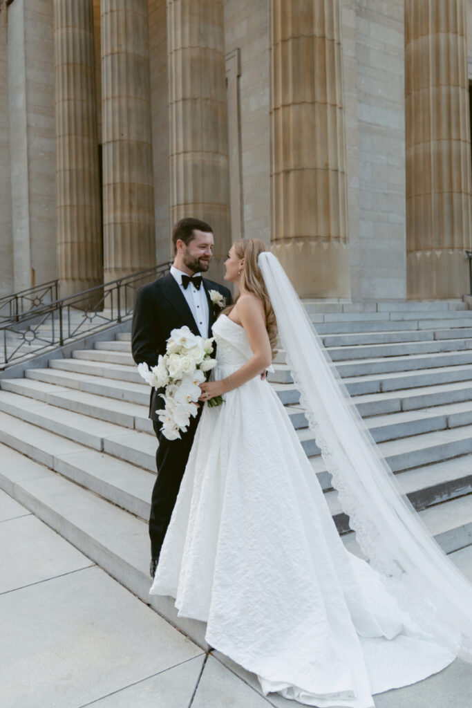 Bride and groom standing together on church steps holding a bouquet.