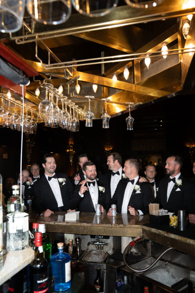 Groomsmen gathered at the bar sharing drinks and conversation during the reception.