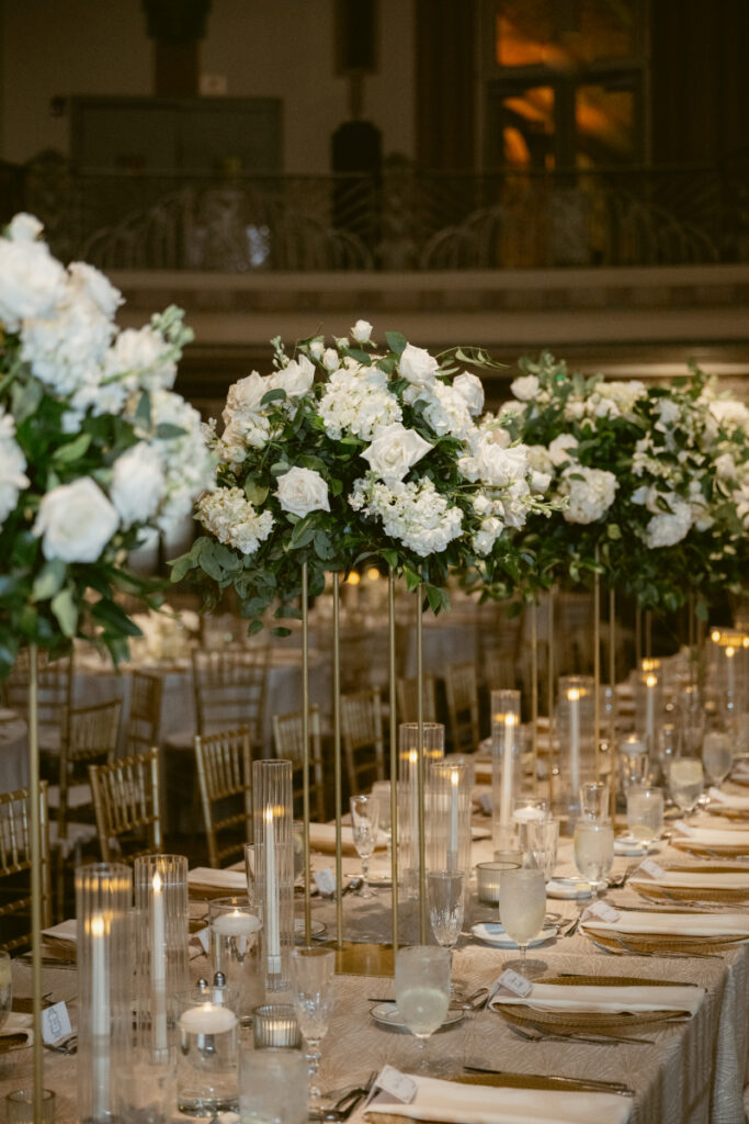 Reception tables lined with white florals and greenery centerpieces.