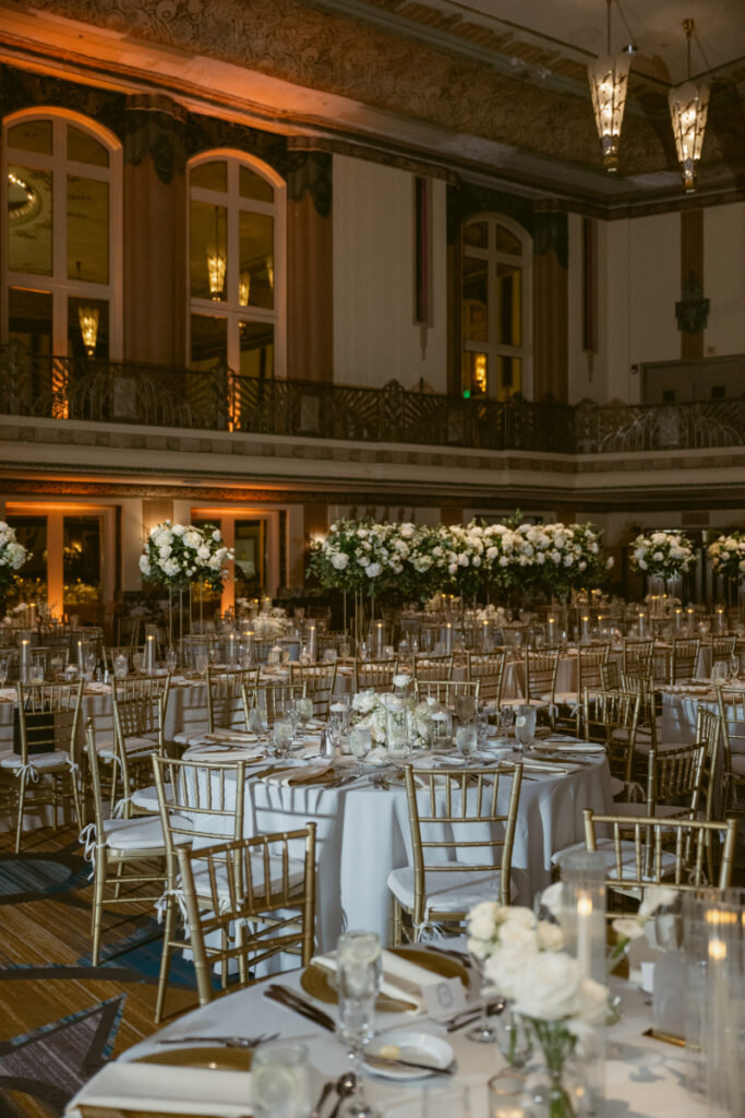 Wide view of reception setup with elegant tables and warm lighting.