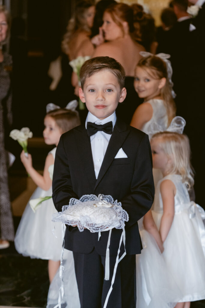 Ring bearer holding pillow during ceremony at St. Peter in Chains for a Hilton Netherland Plaza wedding.