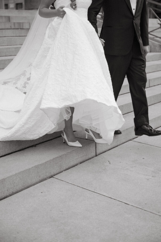 Close-up of the bride’s dress and shoes as the couple walks down the steps.