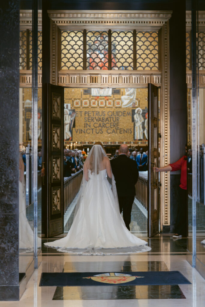 Bride entering the ceremony at St. Peter in Chains Basilica during a Hilton Netherland Plaza wedding.