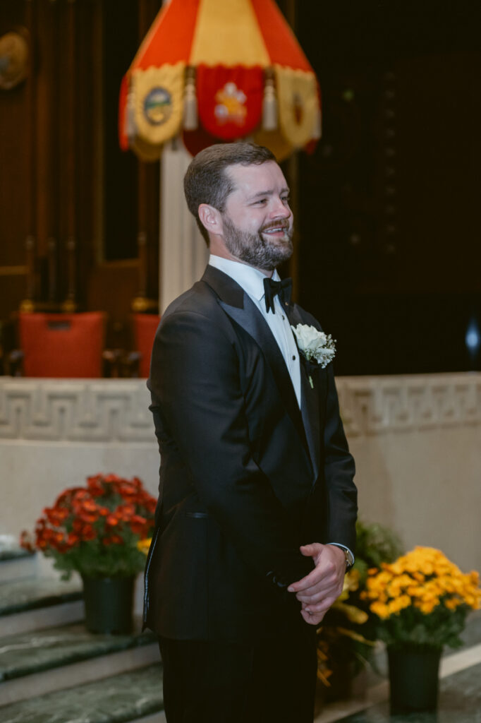 Groom smiling at the altar as the ceremony begins.