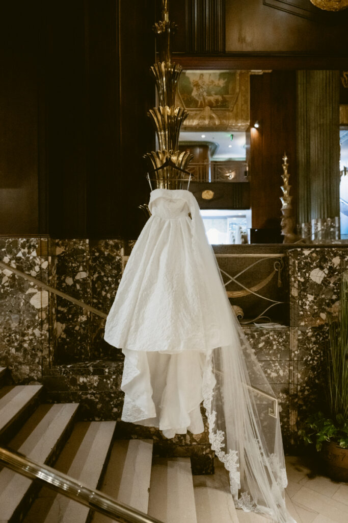 Wedding dress hanging on a grand staircase at a Hilton Netherland Plaza wedding venue.