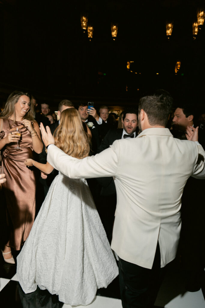 Bride and groom spinning together during a lively dance floor moment.