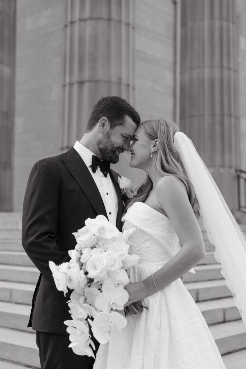 Black and white portrait of the bride and groom smiling together while holding a bouquet at a Hilton Netherland Plaza wedding.