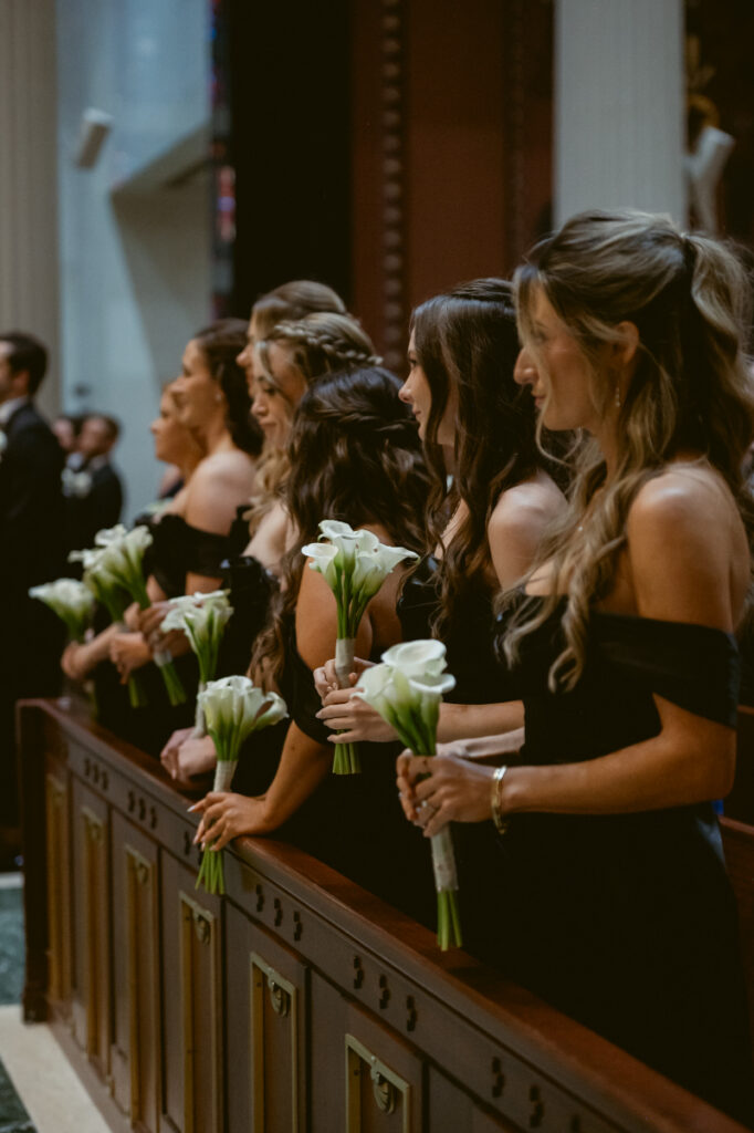 Bridesmaids holding white bouquets and watching the ceremony.
