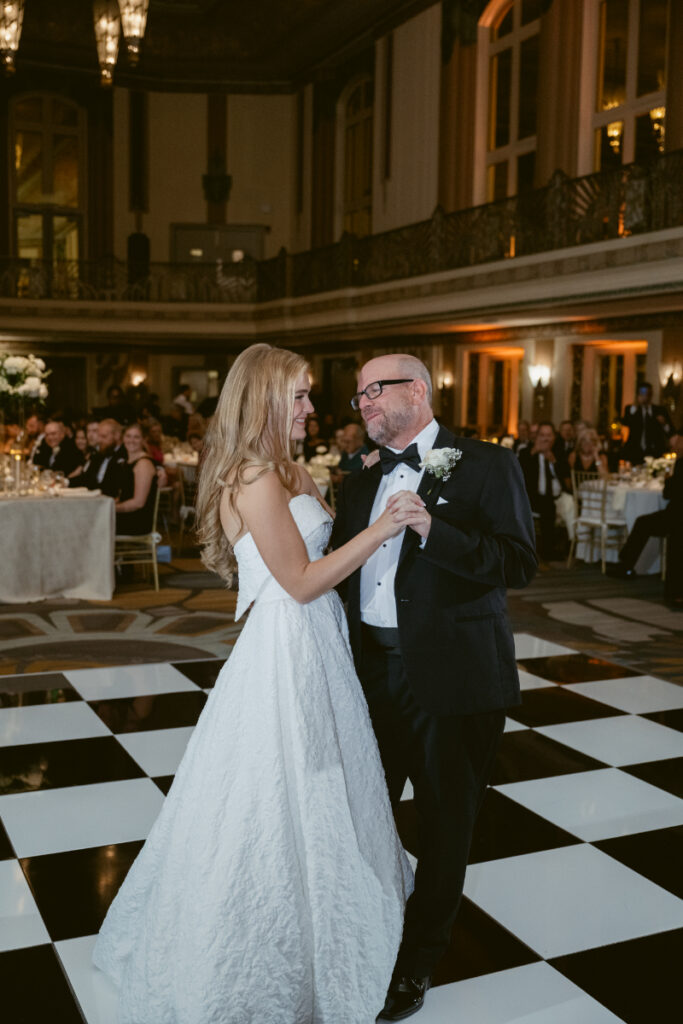 Bride dancing with a parent on the checkered dance floor.