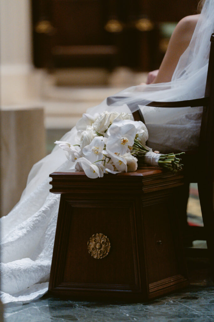 Bridal bouquet resting on a church pew during the ceremony.