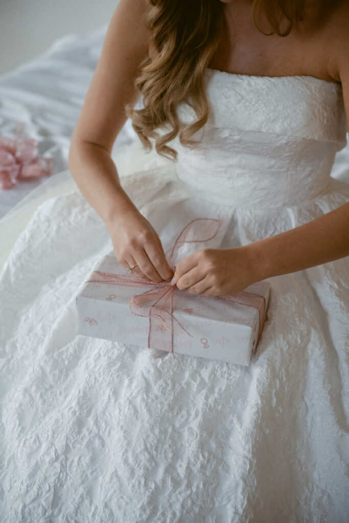 Bride opening a gift while getting ready on her wedding day at a Hilton Netherland Plaza wedding.