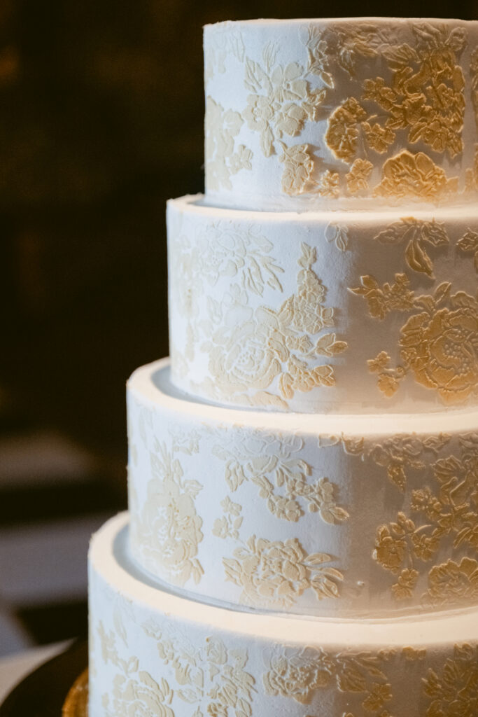 Close-up of textured white wedding cake with floral detailing.