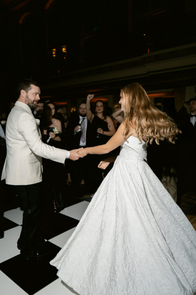 Couple dancing together surrounded by guests during the reception.