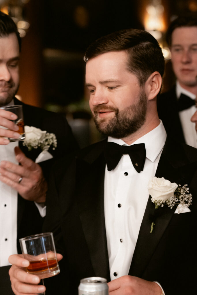 Groom adjusting his boutonniere during a candid moment at the reception.