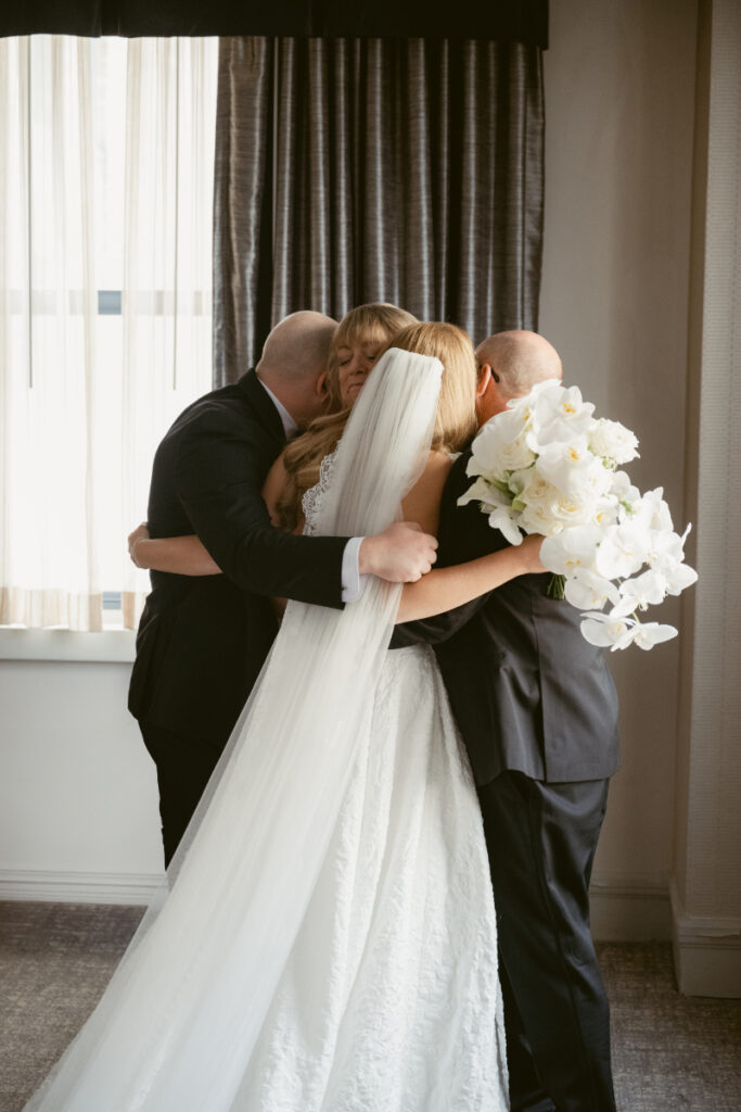 Bride sharing an emotional hug with family during getting ready at a Hilton Netherland Plaza wedding.