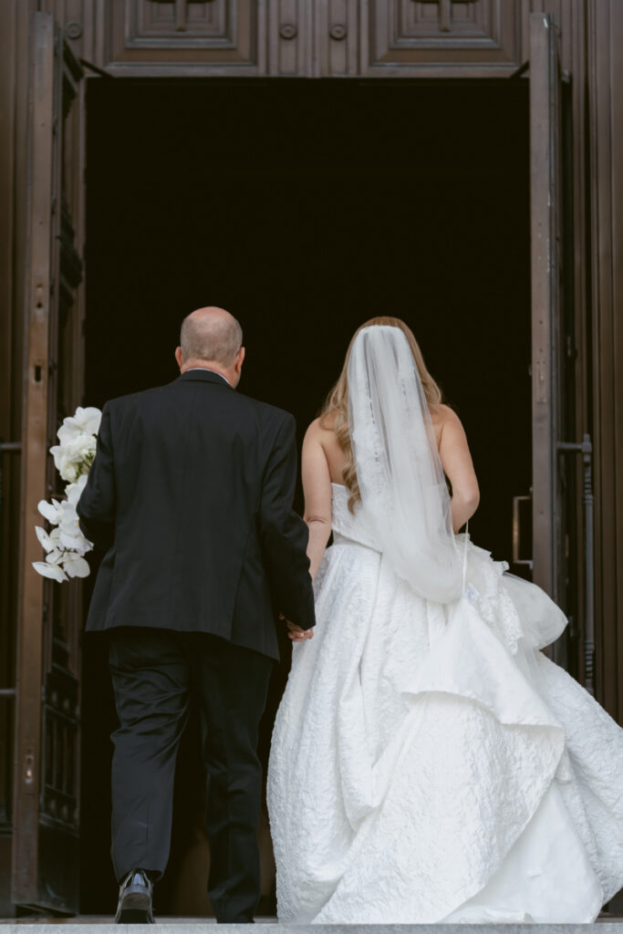 Bride and parent entering the church doors for the ceremony at a Hilton Netherland Plaza wedding.