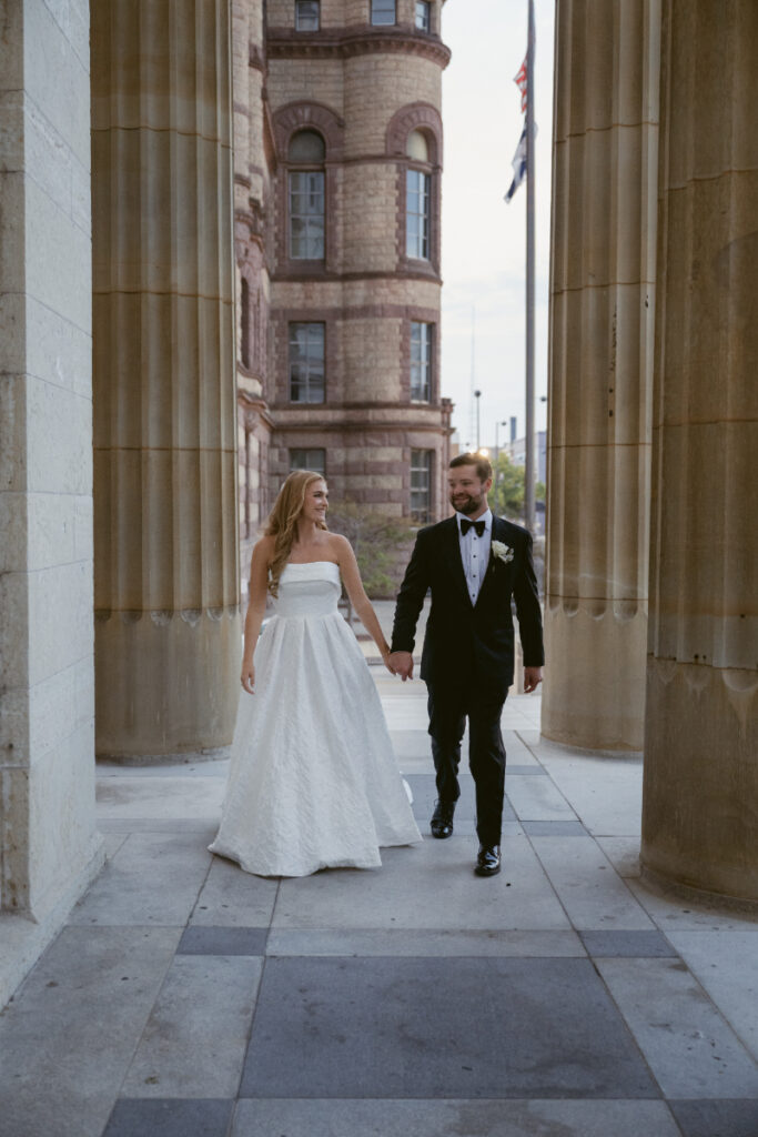 Bride and groom walking together through the church colonnade after their ceremony.