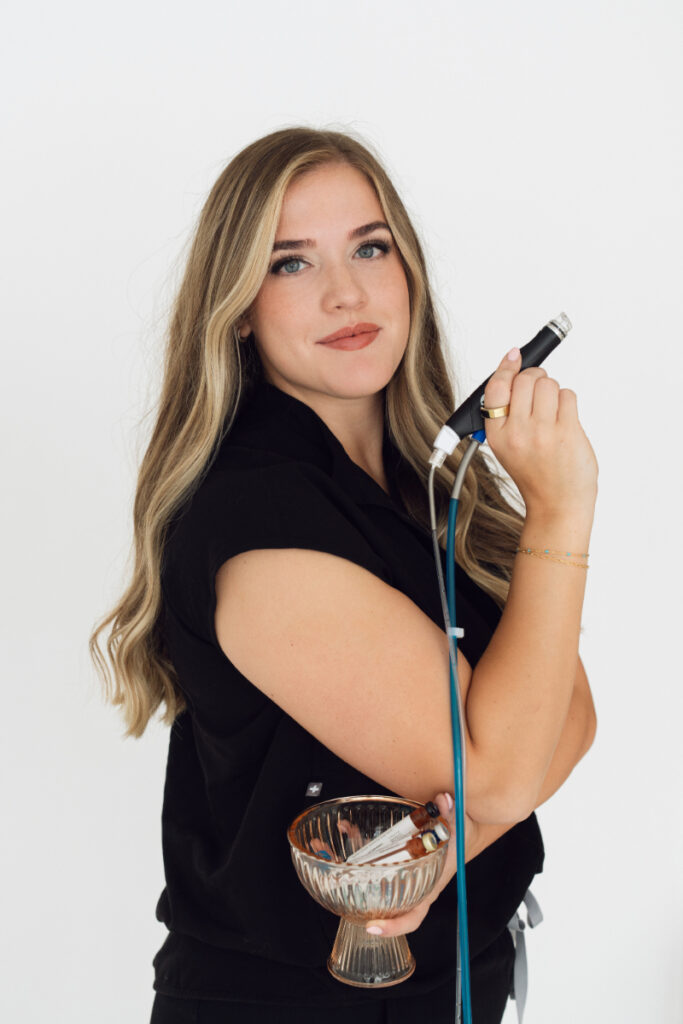 Personal branding photography of a professional woman holding a beauty tool, clean studio headshot with soft lighting
