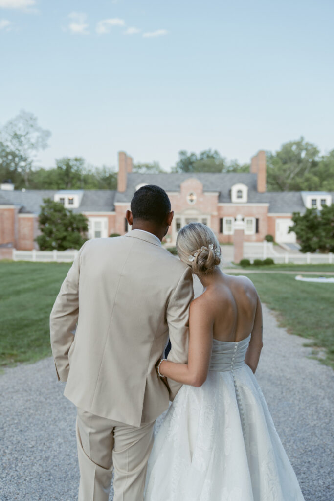 Bride and groom walk together outside a historic estate at one of Cincinnati's beautiful garden wedding venues.