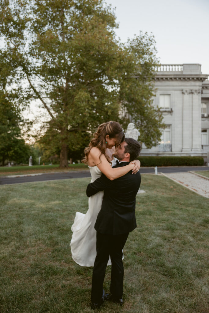 Bride and groom embrace during sunset portraits outside a historic estate.