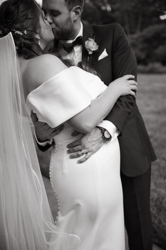 Bride and groom share a romantic embrace during outdoor wedding portraits.