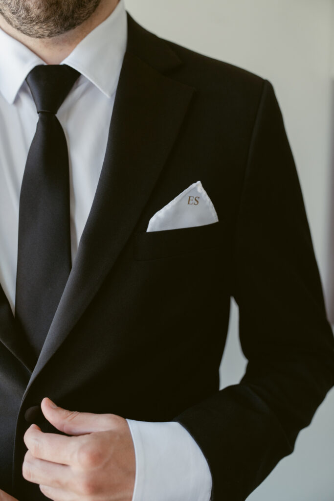 Groom adjusts his suit and monogrammed pocket square at The Palomar, one of Ohio wedding venues.