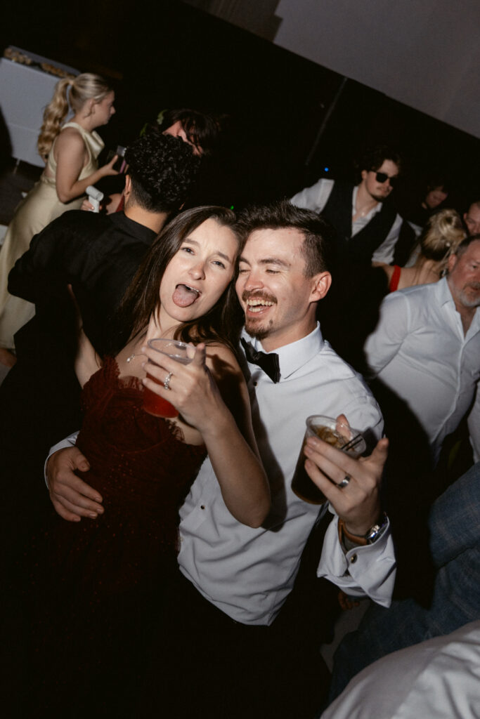 Wedding guests laugh and celebrate together on the packed dance floor during the reception.