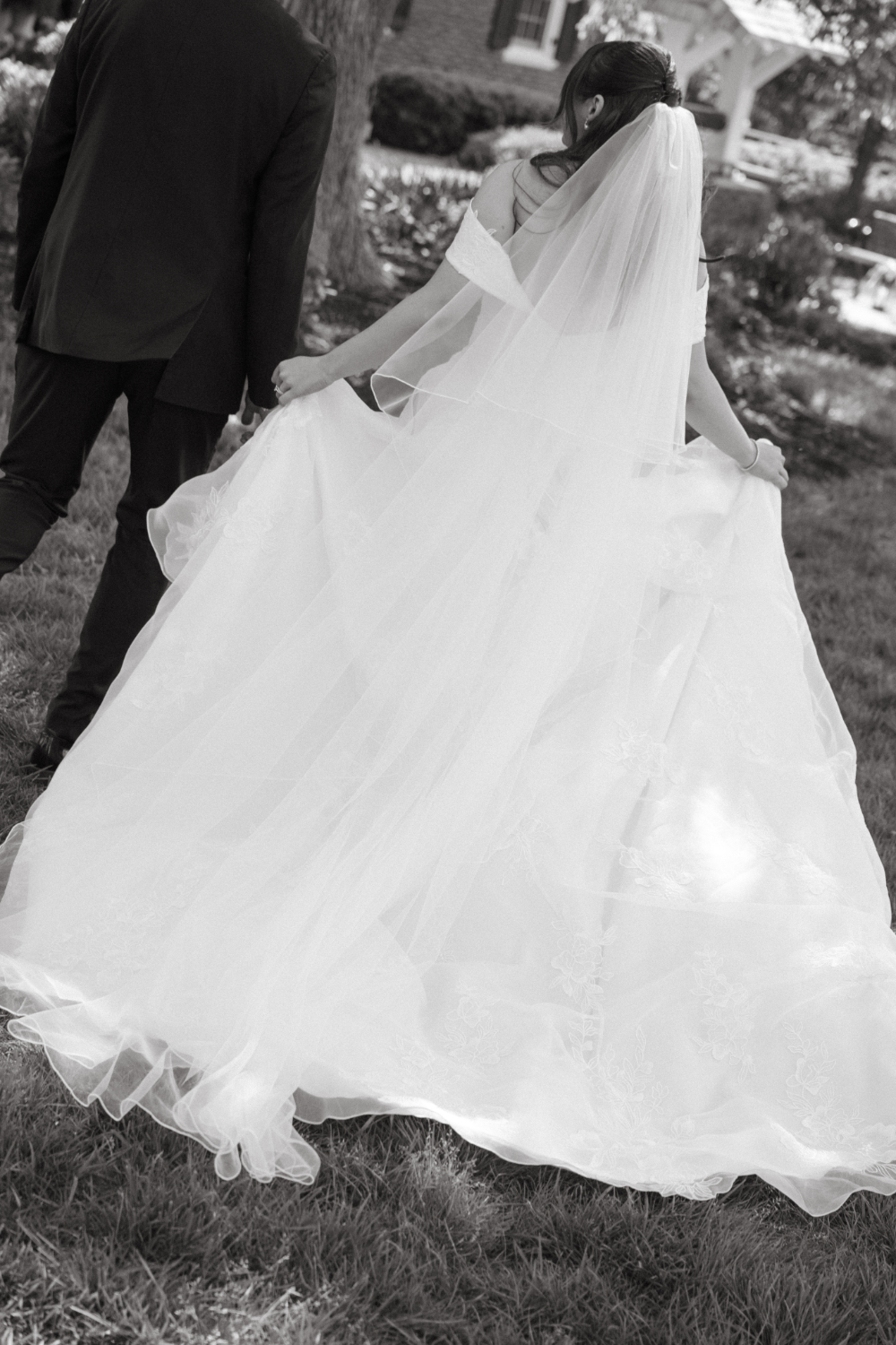 Close-up of a bride holding the layers of her flowing wedding dress while walking outdoors.